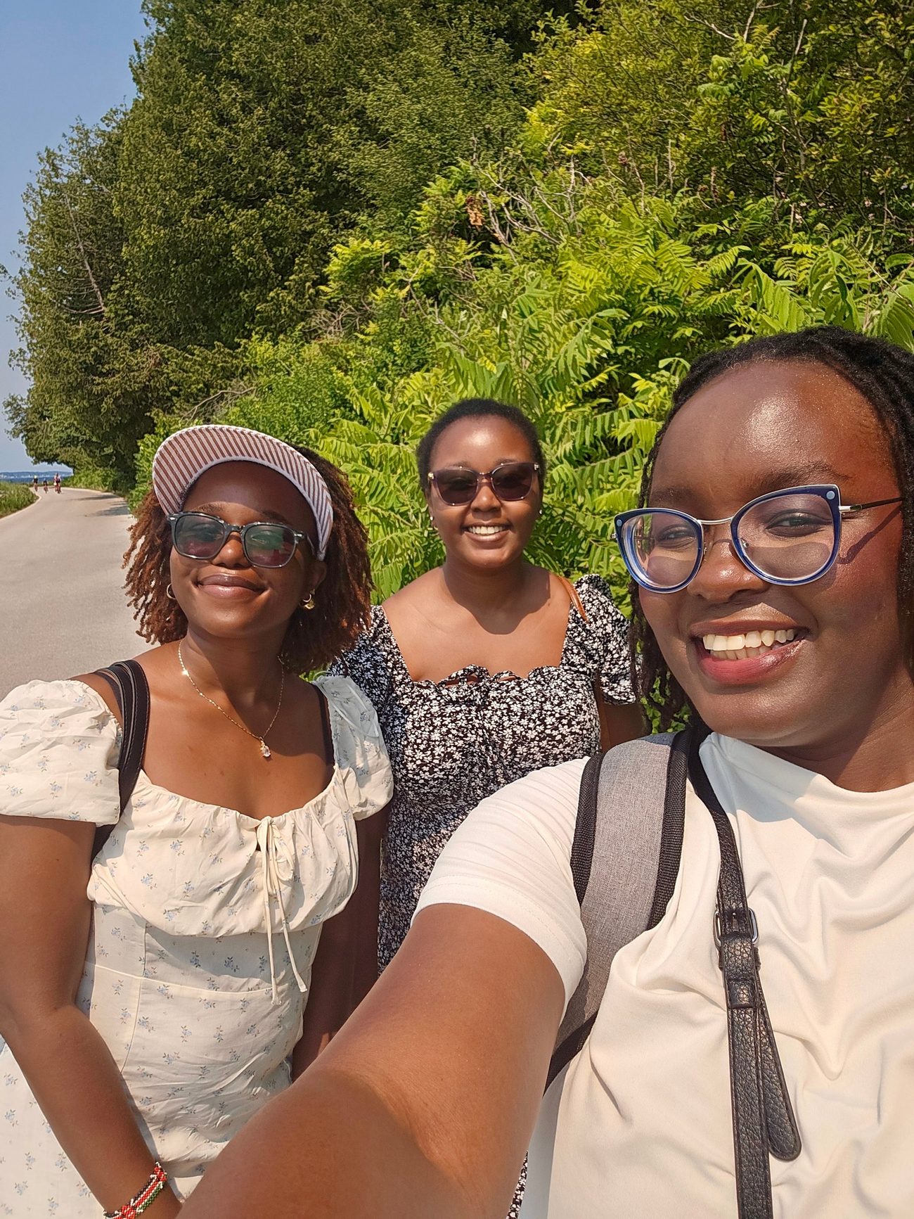 Cynthia and two friends on a tree-lined road